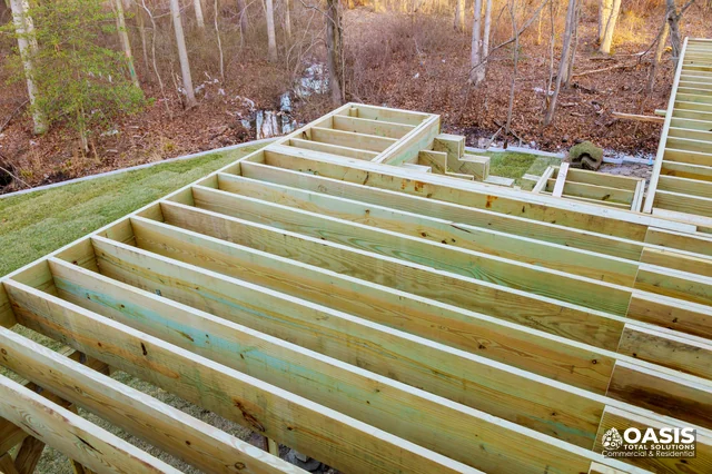 Joists and deck framing overlooking a wooded yard
