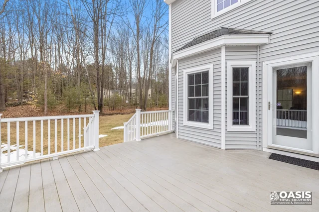 Backyard deck with white railings and gray siding home