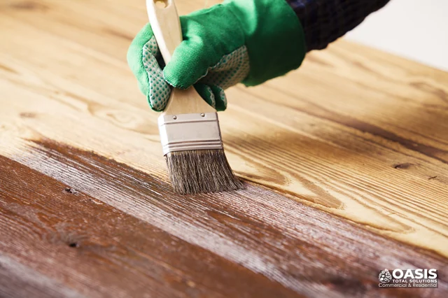 Applying wood stain to deck boards with brush