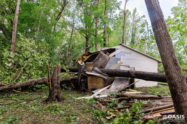 Storm-damaged shed crushed by fallen tree