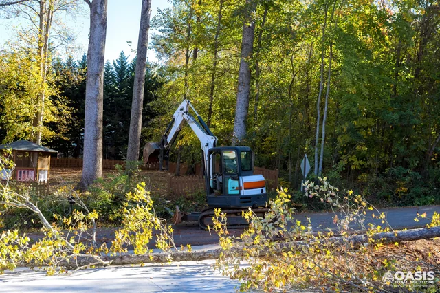 Excavator removing downed trees near homes