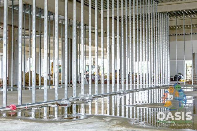 Long run of metal studs reflecting on wet slab in commercial build-out