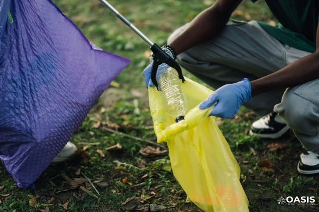 Close-up of gloved hands collecting plastic bottle with litter grabber