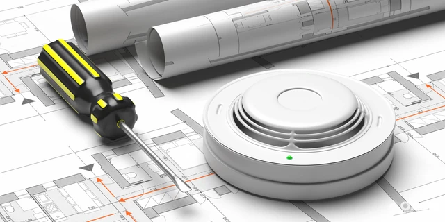 Smoke detector and screwdriver on architectural floor plans