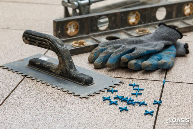 Tiling tools with spacers, trowel and gloves on floor