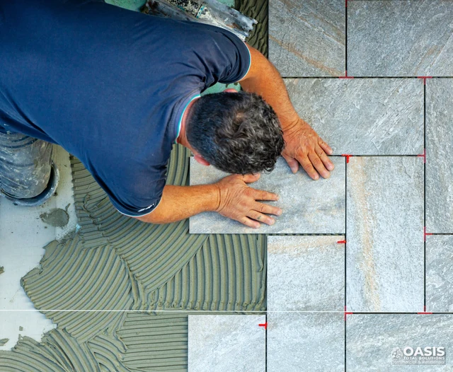 Contractor laying stone-look tiles in staggered pattern