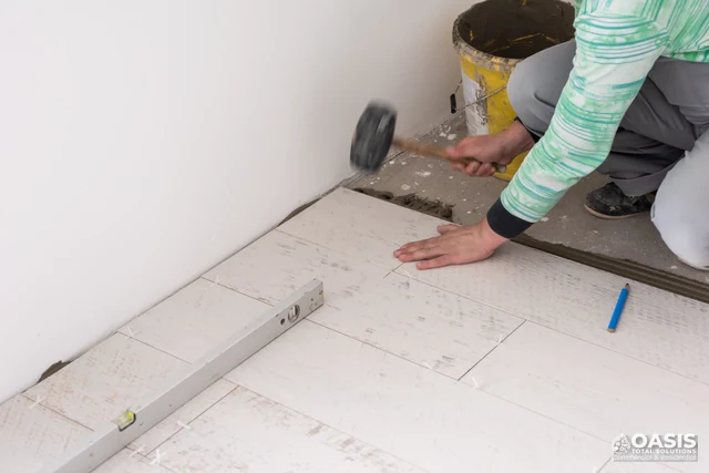 Tapping tile into place with rubber mallet