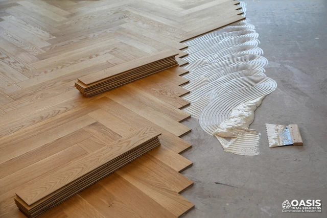 Herringbone wood floor—adhesive spread and boards staged