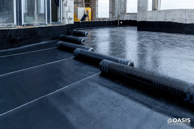 Rolling waterproofing membrane across concrete slab