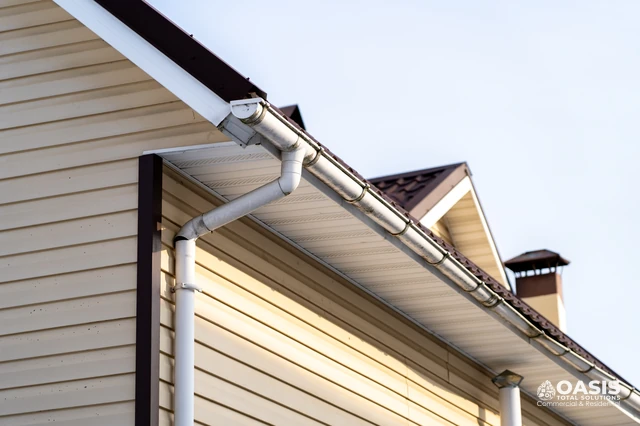 White seamless gutters and downspout on beige siding