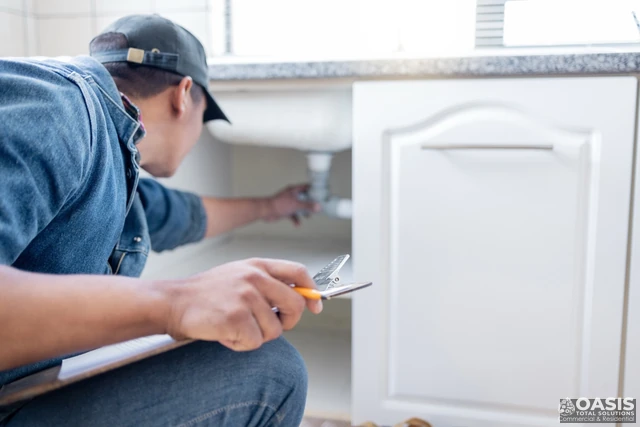 Inspecting under-sink plumbing with clipboard