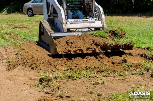 Skid steer grading and stripping soil