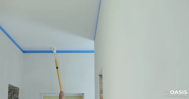 Rolling paint along a ceiling edge with taped line