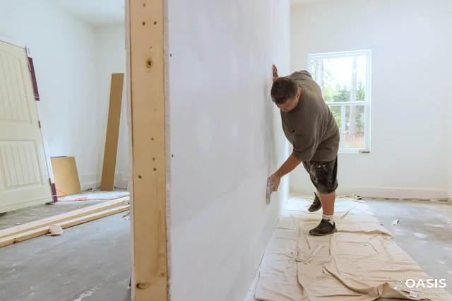 Contractor sanding drywall for a smooth finish