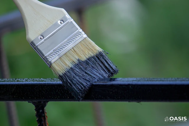 Close-up brush painting black enamel on a metal railing