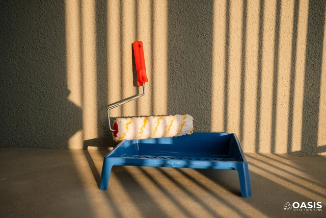 Paint roller resting on tray with warm light and shadows