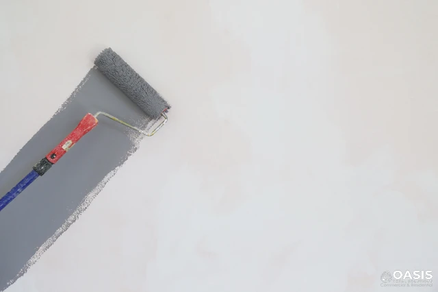 Rolling a gray coat of paint on primed wall