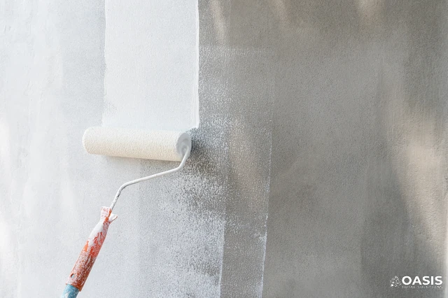 Rolling white paint on a textured exterior wall