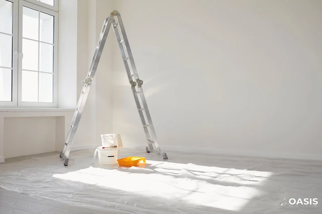 Bright room with ladder and paint setup on floor protection