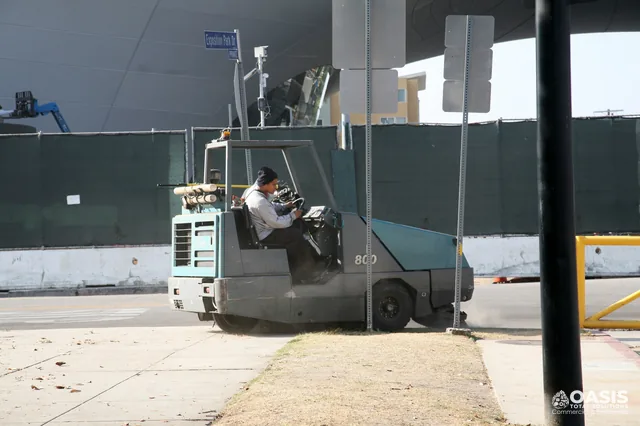 Operator driving a ride-on sweeper for lot cleaning