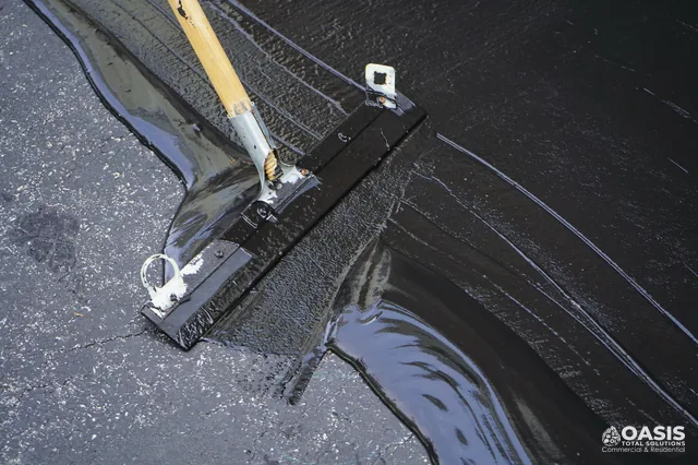 Squeegee applying fresh sealcoat along the edge line