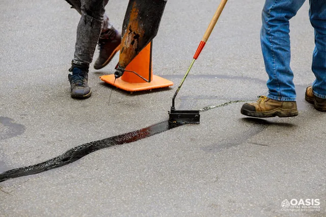 Crew applying hot-pour sealant to a long crack