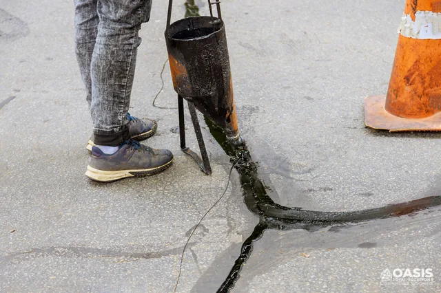Pour pot filling and sealing an asphalt crack
