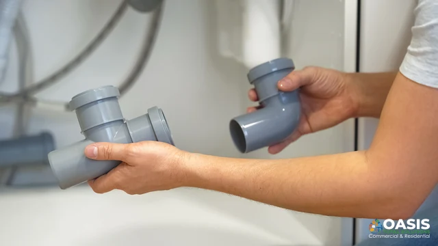 Hands holding gray polypropylene drain fittings