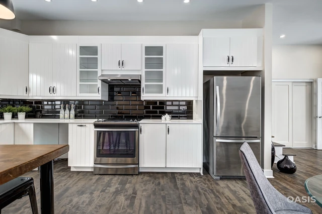 Straight-on view of renovated kitchen with stainless fridge and range