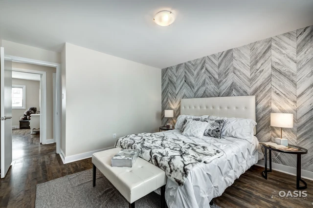 Finished bedroom with chevron accent wall and upholstered headboard
