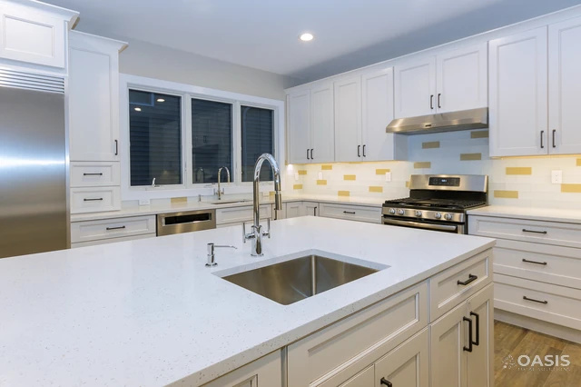 Finished kitchen featuring large quartz island and modern backsplash