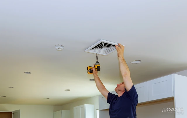 Technician mounting a ceiling vent with a drill