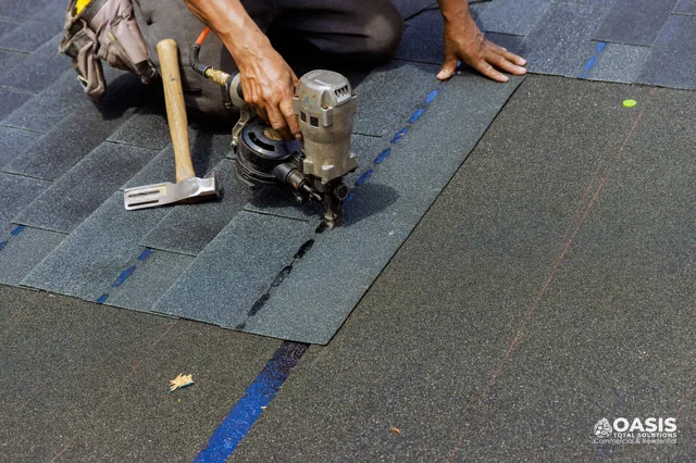 Close-up of nail gun fastening architectural shingles along layout line