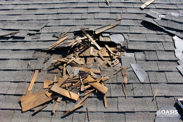 Storm damage hole in asphalt shingles exposing decking