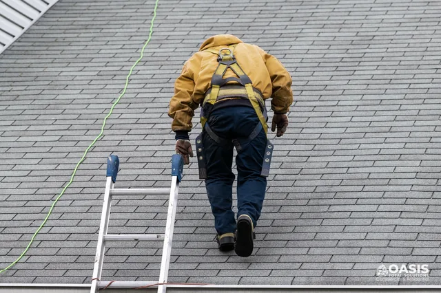 Technician on ladder with safety harness ascending shingle roof