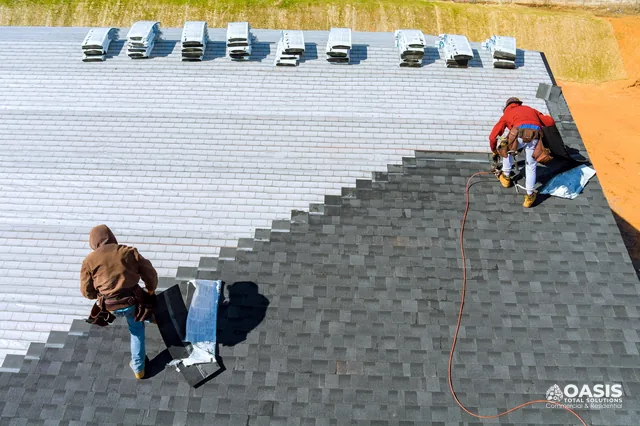 Aerial view of crew laying new shingle courses over underlayment