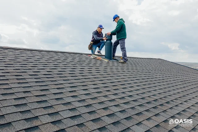 Roofers positioning vent on asphalt shingle roof
