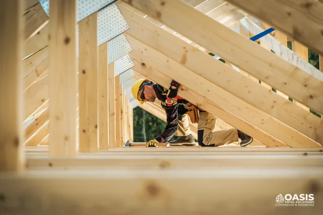 Carpenter working inside roof truss framing with safety gear