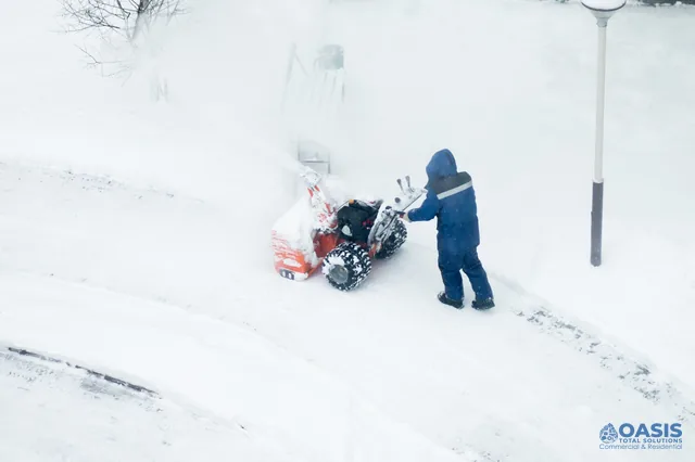 Operator using a snow blower to clear a path during a storm