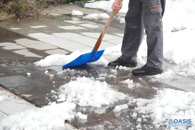 Clearing slush from a paved walkway with a blue shovel