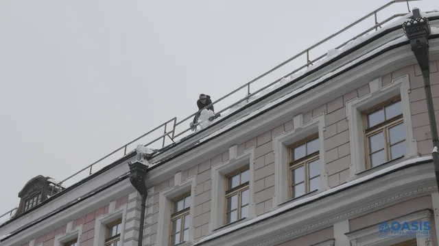 Worker removing snow from a rooftop edge