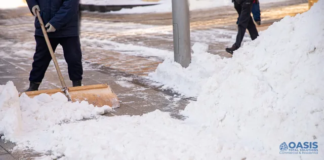 Crew pushing snow on a city sidewalk